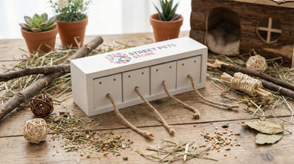 Small wooden pet toy store with ropes on a wooden surface with plants and a small house in the background.